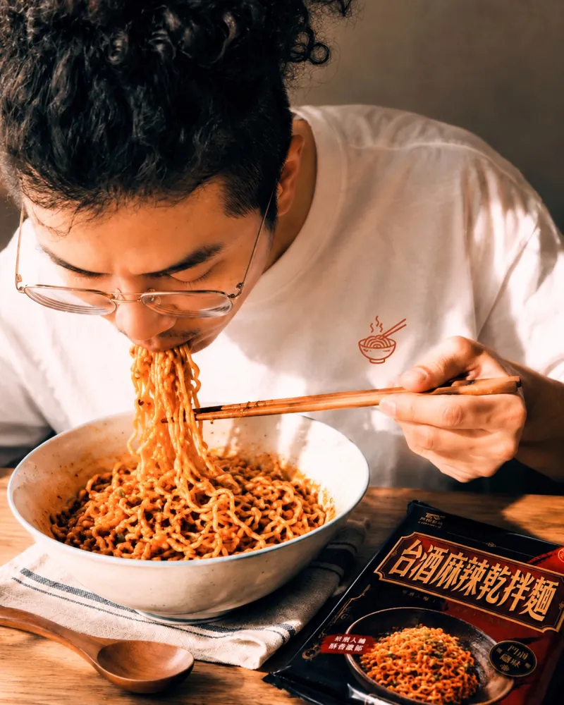 대만 비빔면: 台酒麻辣乾拌麵을 크게 한입 먹는 남성, 테이블 위의 포장