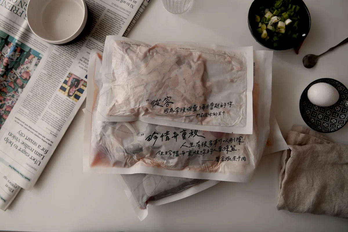 報紙上疊著用紙包好、寫著手寫字的門前隱味燉煮牛肉,旁邊有蔥花和雞蛋