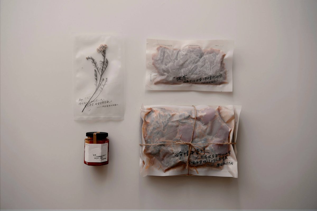門前隱味宅配內容：用紙包好的燉煮牛肉與湯包，旁邊放著一罐迷你辣