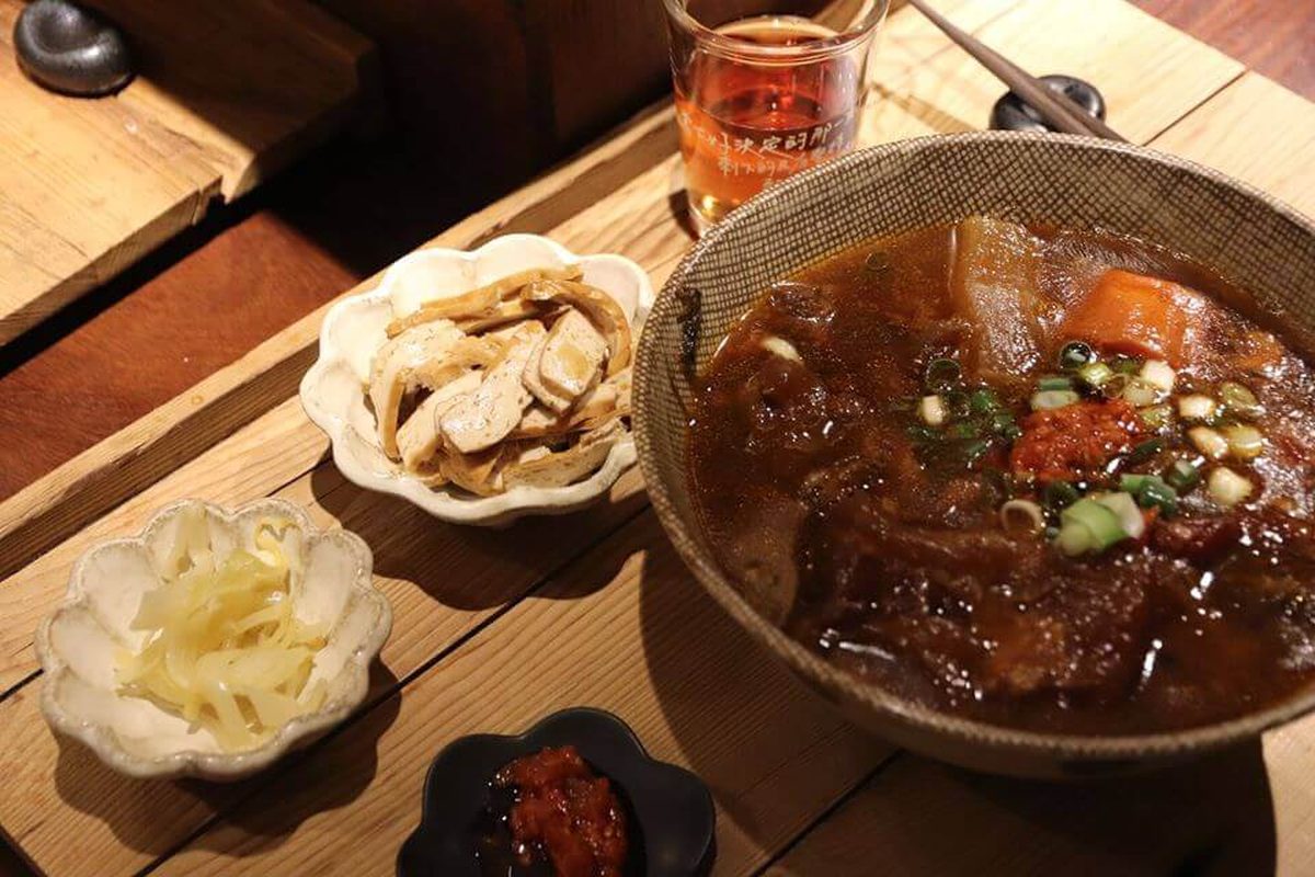 一大碗門前隱味燉煮牛肉,旁邊擺著幾樣小菜和一杯茶